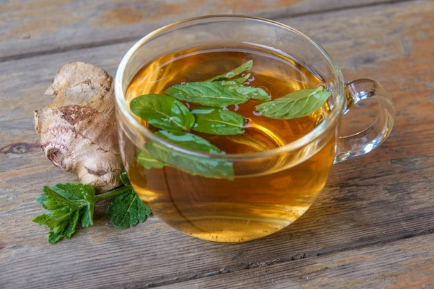 Tasty herbal tea in glass teapot on old wooden table