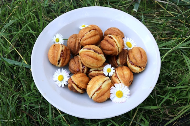 Tasty home made nuts with condensed milk in a white plate with flowers on the grass