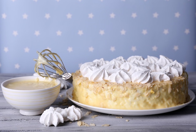 Tasty homemade meringue cake on wooden table on blue background