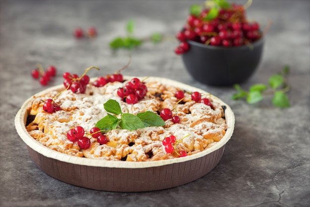 Tasty homemade pie and fresh red currants in dark bowl on grey