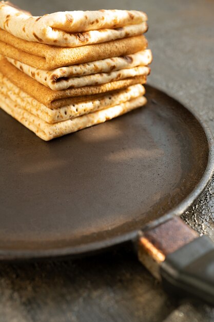 Tasty homemade rustic pancake in a frying pan on wooden table. Maslenitsa food.