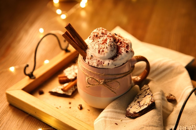 Tasty hot drink with whipped cream and cookies on wooden table closeup