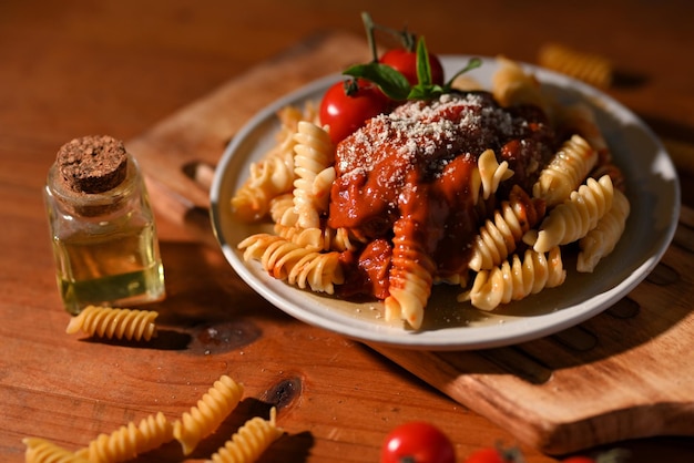 Tasty Italian pasta Fusilli with tomato sauce and parmesan cheese in a vintage dining wood table