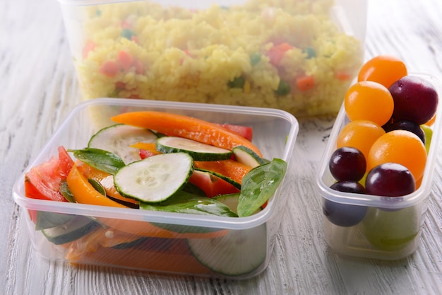 Tasty lunch in plastic containers on wooden table close up