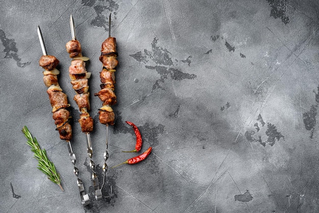 Photo tasty marinated meat skewers set, on gray stone table background, top view flat lay, with copy space for text