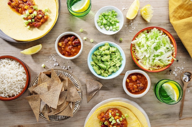 Tasty mexican food with fresh avocado sauce burittos tacos chilli con carne on wooden table