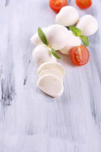 Tasty mozzarella cheese with basil and tomatoes on wooden table