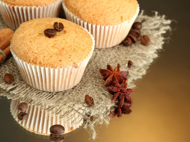 Tasty muffin cakes on burlap, spices and coffee seeds, on brown background