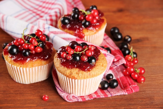 Tasty muffins with berries on wooden table