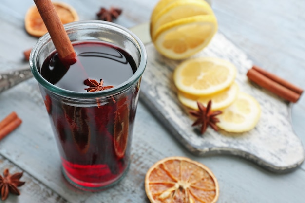 Tasty mulled wine and spices, on blue wooden background, close-up