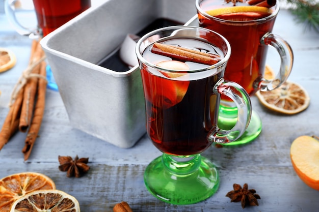 Tasty mulled wine and spices on blue wooden background close-up