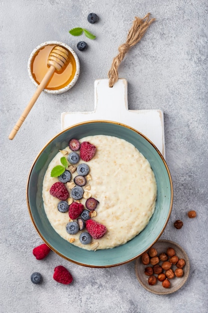 Tasty oatmeal with berries in bowl on white surface