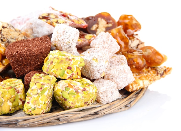 Tasty oriental sweets on wicker tray isolated on white