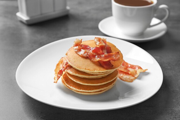 Tasty pancakes with bacon on plate