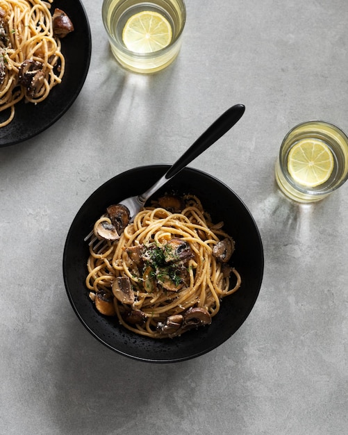 Tasty pasta with mushrooms served on plate with greens cheese and spice on a dark background