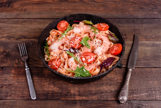 Tasty pasta with shrimp and tomato on a frying pan