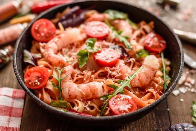 Tasty pasta with shrimp and tomato on a frying pan