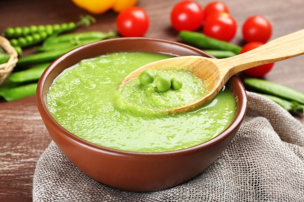 Tasty peas soup and cherry tomatoes on table close up