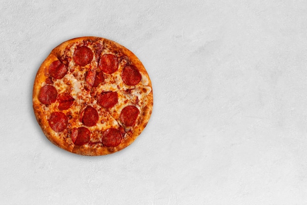 Tasty pepperoni pizza on bright concrete surface with copy space.