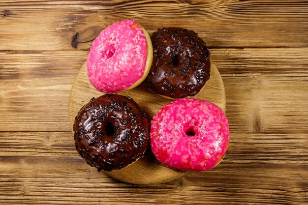 Tasty pink and chocolate donuts on a wooden table Top view