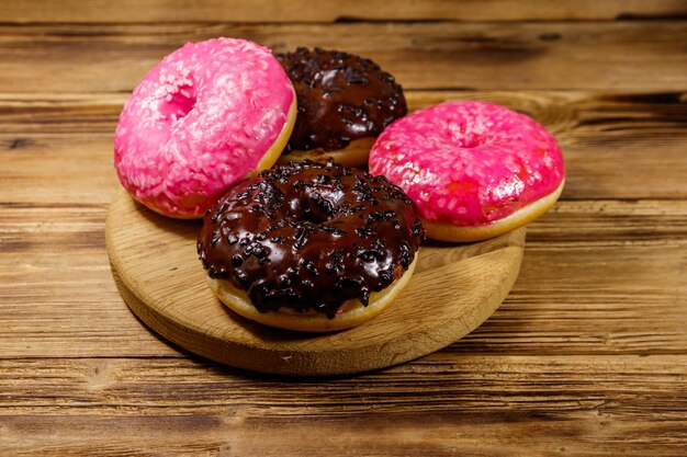 Tasty pink and chocolate donuts on a wooden table