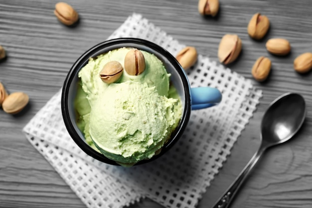 Tasty pistachio icecream with nuts in mug on table