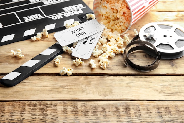 Photo tasty popcorn tickets clapboard and movie reel on wooden background