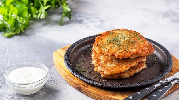 Tasty potato pancakes on a frying pan with sour cream