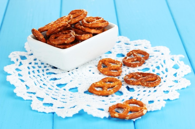 Tasty pretzels in white bowl on wooden table closeup