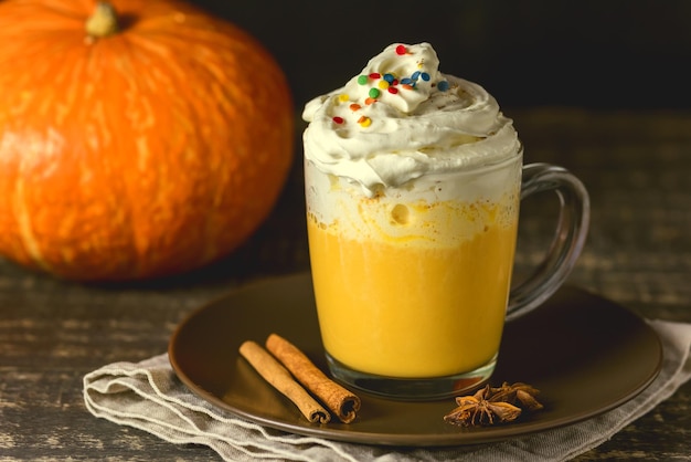 Tasty Pumpkin Latte with Spices Whipped cream on top on a Dark Wooden Background Autumn Hot Beverage Toned