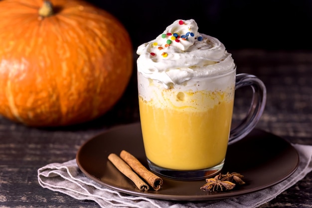 Tasty Pumpkin Latte with Spices Whipped cream on top on a Dark Wooden Background Autumn Hot Beverage