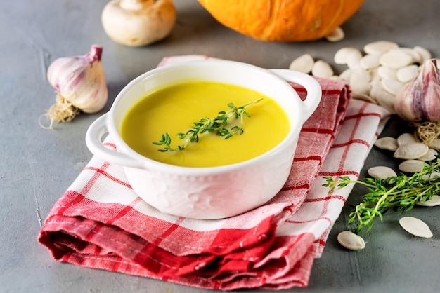 Tasty Pumpkin Soup with Cream on Gray Background Raw Pumpkin Herbs Garlic Horizontal