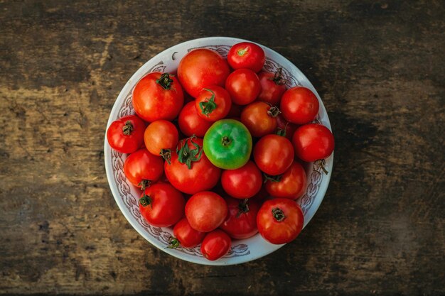 Tasty red, yellow and green tomatoes with green verdure on plate