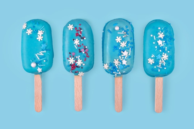 Tasty and refreshing ice cream on sticks. Blue mint ice cream popsicles on blue background. Minimal summer concept. Flat lay, free copyspace for text