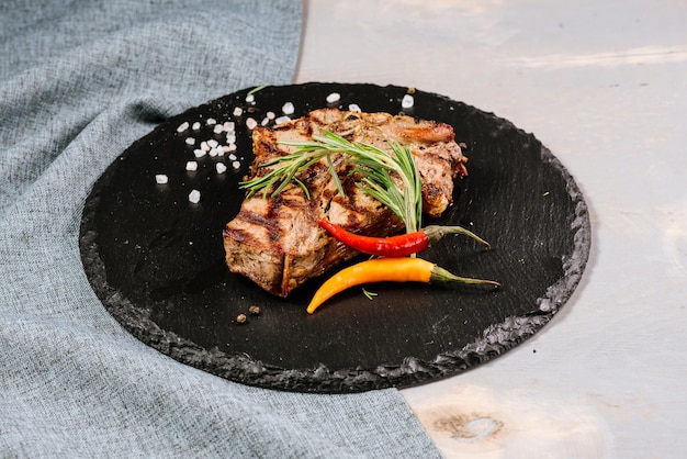 Tasty roasted steak with spices on the wooden background