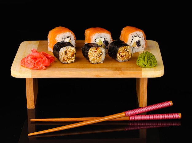 Tasty rolls served on wooden plate isolated on black