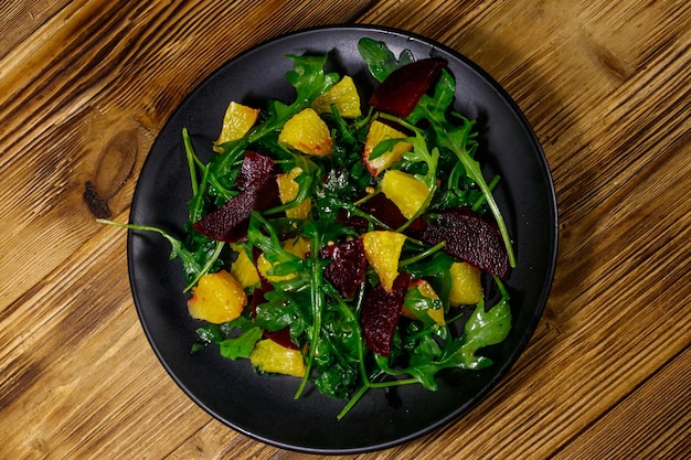 Tasty salad of fresh arugula beetroot and oranges on wooden table Top view Healthy food or vegetarian concept