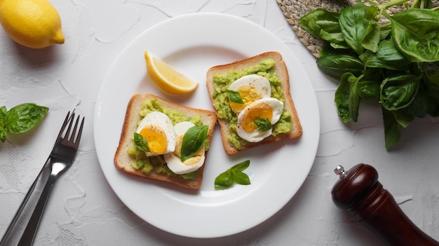 Tasty sandwiches with boiled egg avocado and spinach served on white textured table flat lay