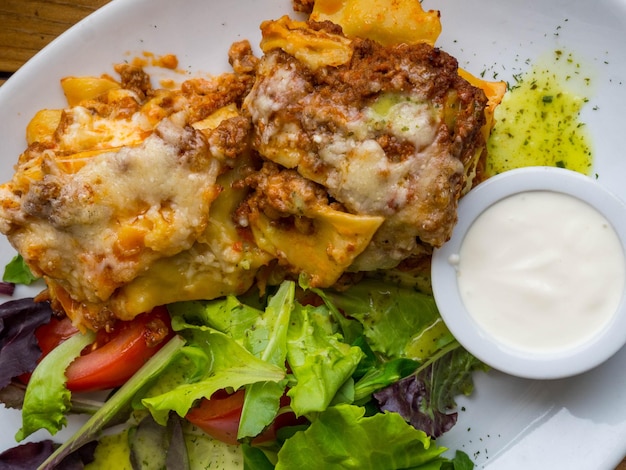 Tasty serving of traditional Italian lasagne with spicy tomato based ground beef and melted mozzarella cheese between layers of noodles with cream and green leafs