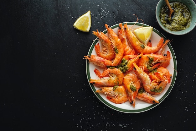 Tasty shrimps with spices and sauce on plate on dark surface