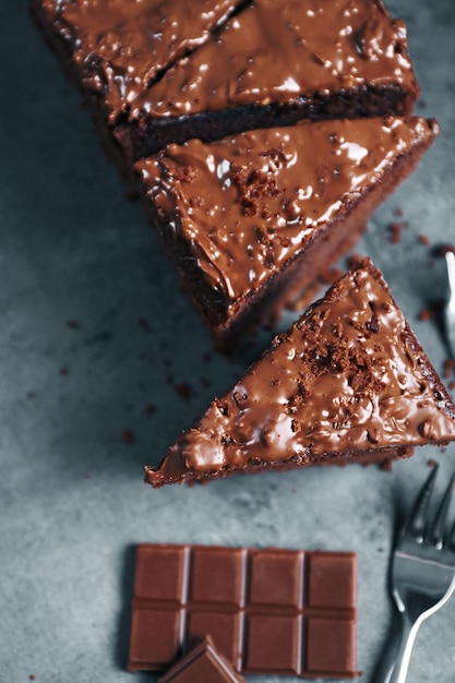 Tasty sliced cake with chocolate and forks on grey background close up