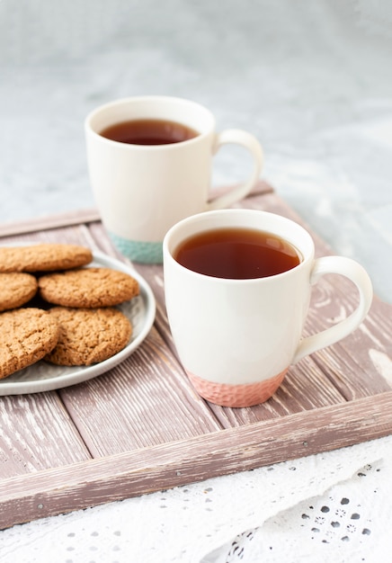 A tasty snack: two cups of tea and a plate of cookies.	