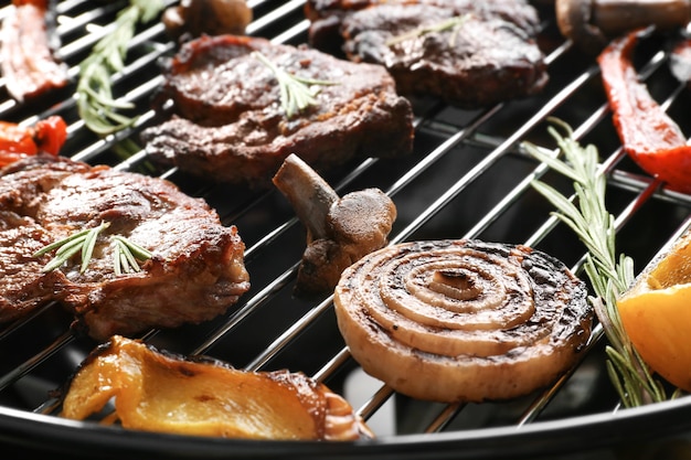 Tasty steaks and vegetables on barbecue grill close up