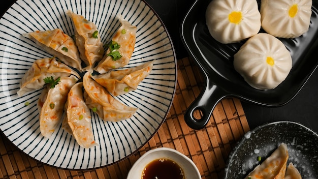 Tasty steamed Chinese dumplings or Japanese gyoza dumplings with a plate of pork buns on the table