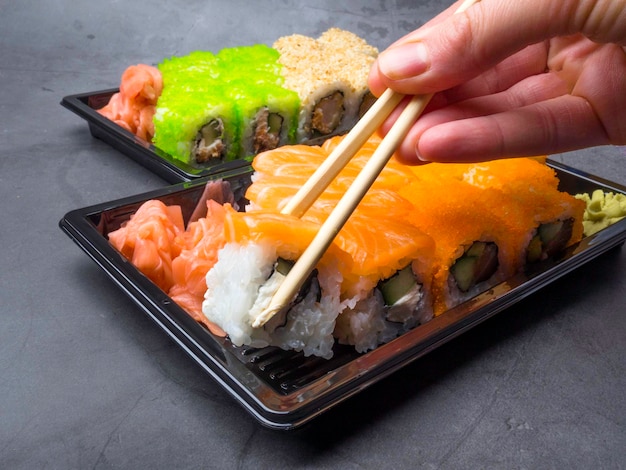 Tasty sushi bar Eating Sushi with chopsticks California Sushi roll set with salmon vegetables fish caviar closeup Japan restaurant menu