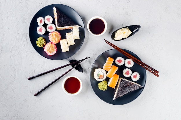 Tasty sushi rolls set with sauces, chopsticks, ginger on table