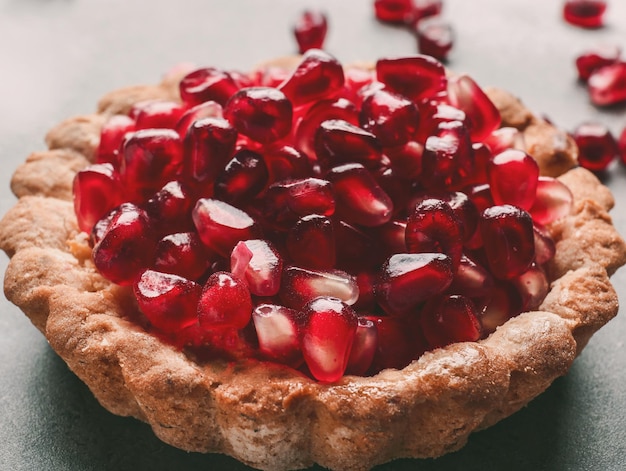 Tasty tart with fresh seeds of pomegranates on table closeup