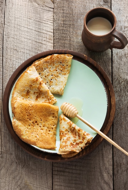 Tasty traditional russian breakfast of pancakes with honey on plate.