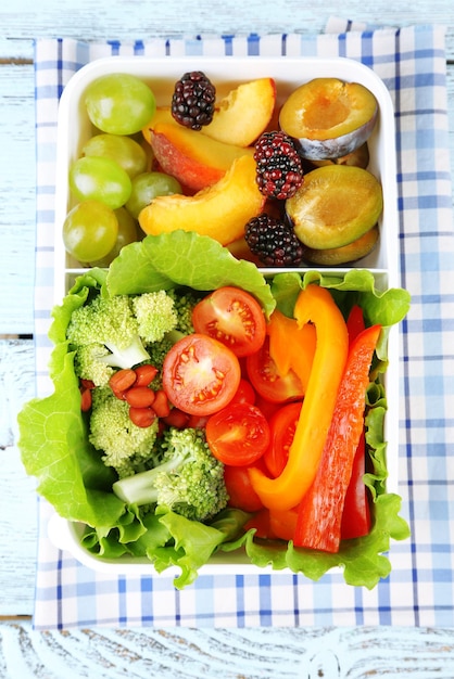 Tasty vegetarian food in plastic box on wooden table