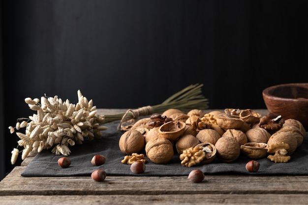 Tasty walnuts with cracked split nutshells on rustic napkin and wood table